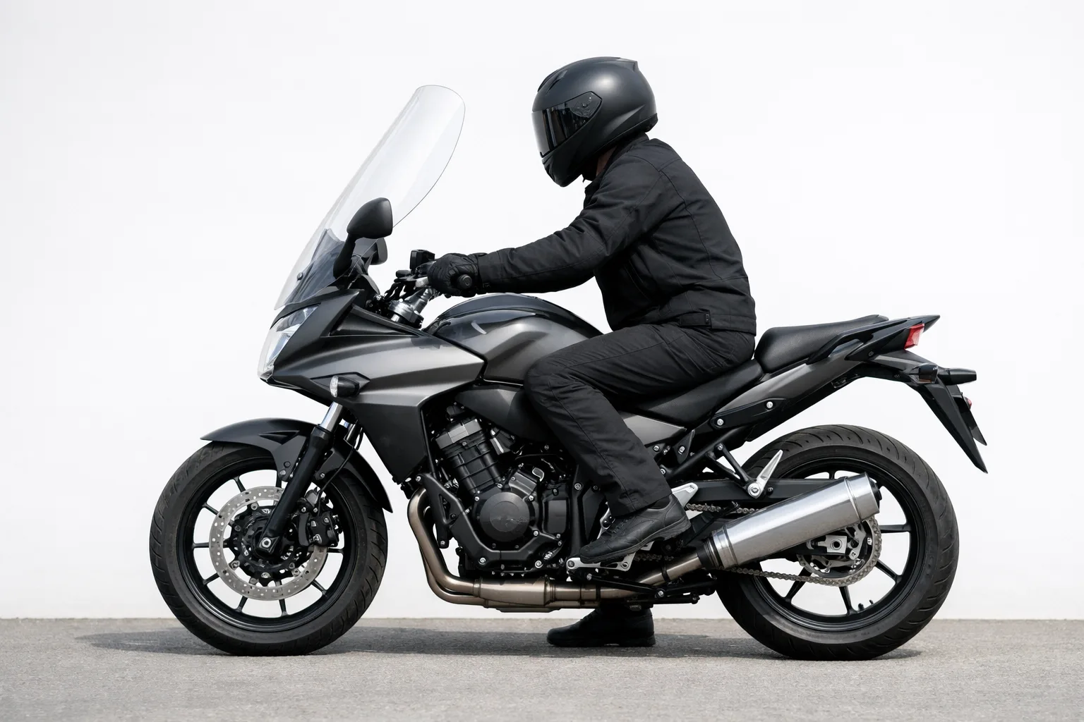 Profil d’une moto avec un pilote assis derrière une bulle transparente.