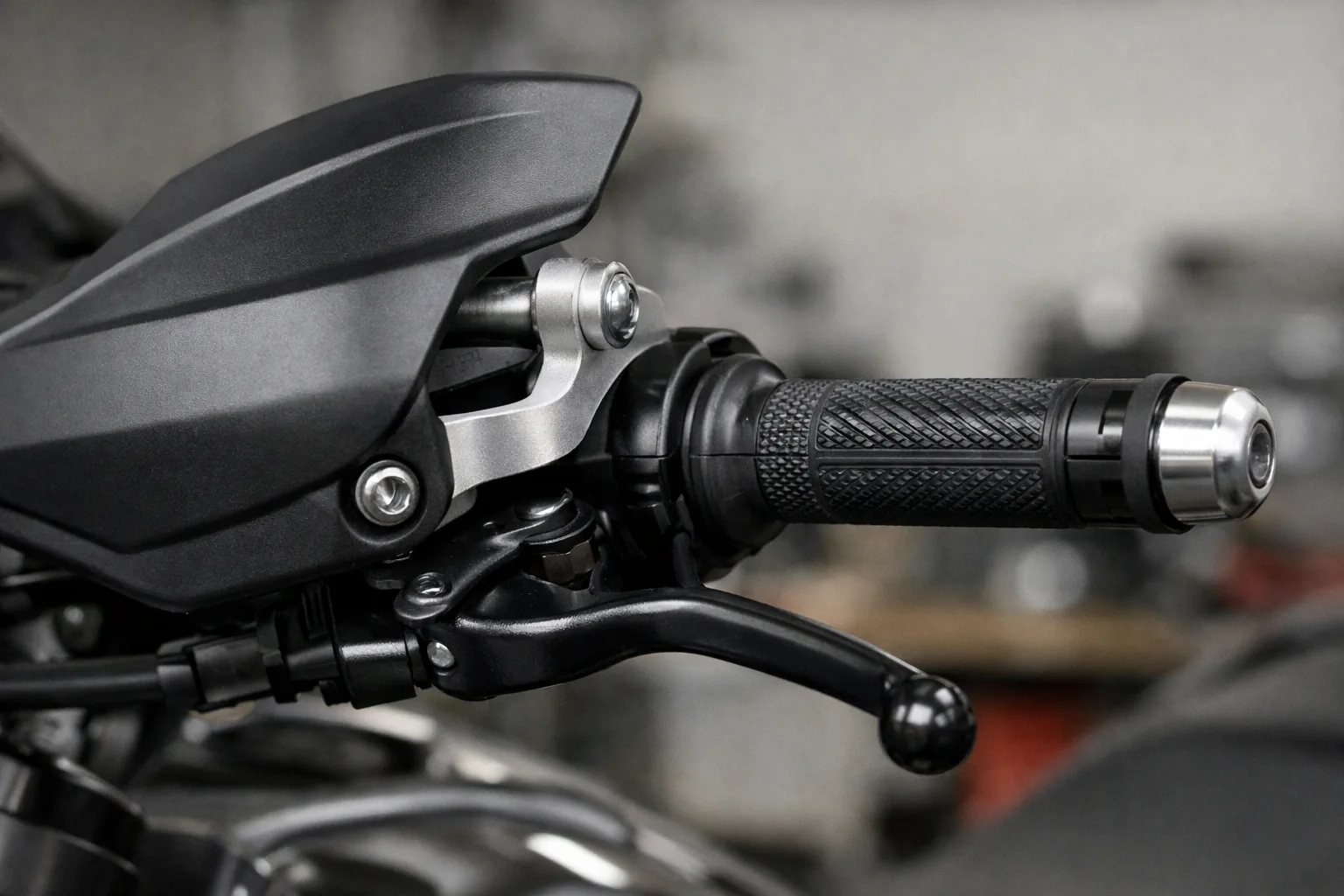 Détail du support d’un protège-main installé près de la poignée et du levier d’une moto.