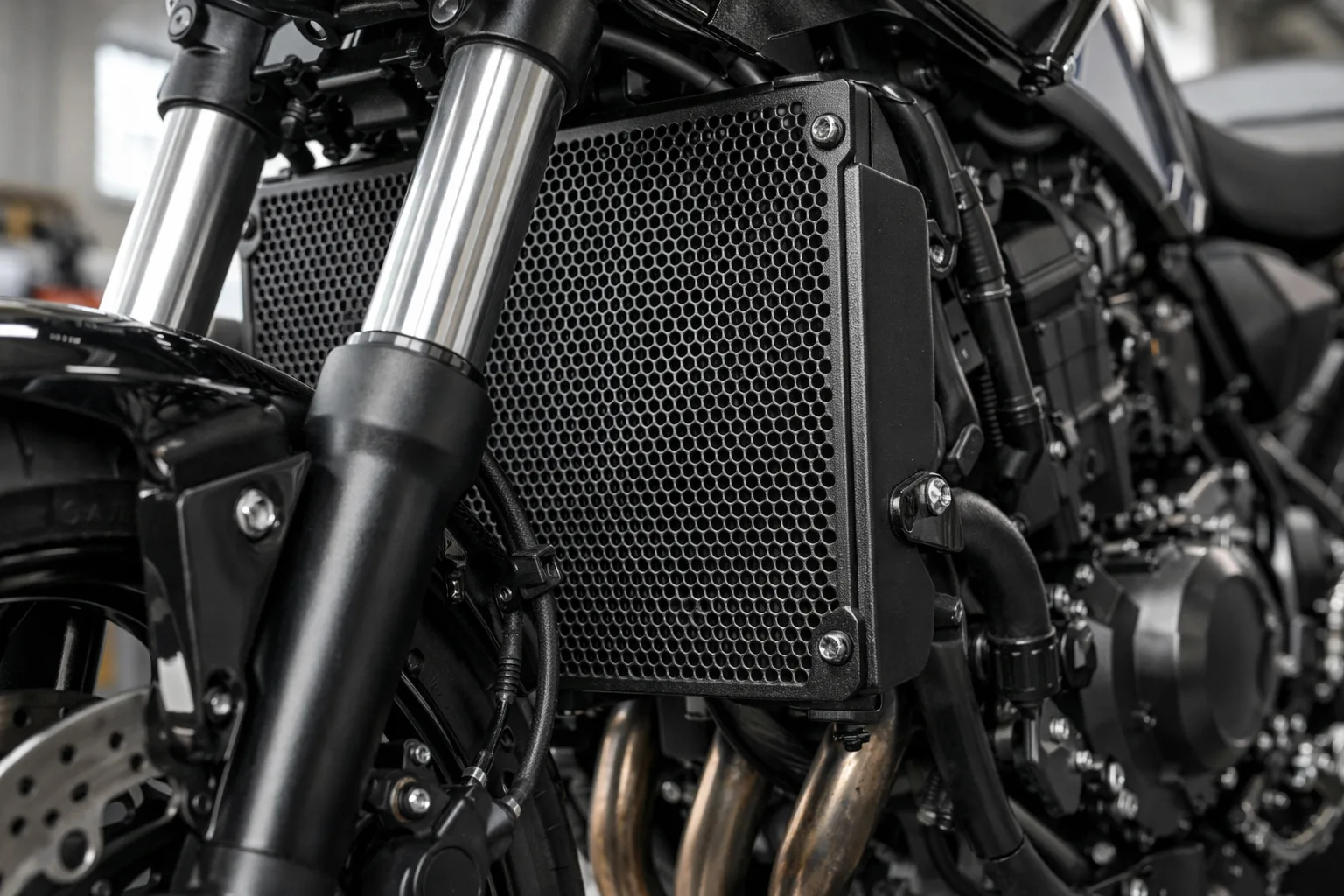 Grille de protection fixée devant le radiateur d’une moto, avec son maillage et ses attaches visibles.