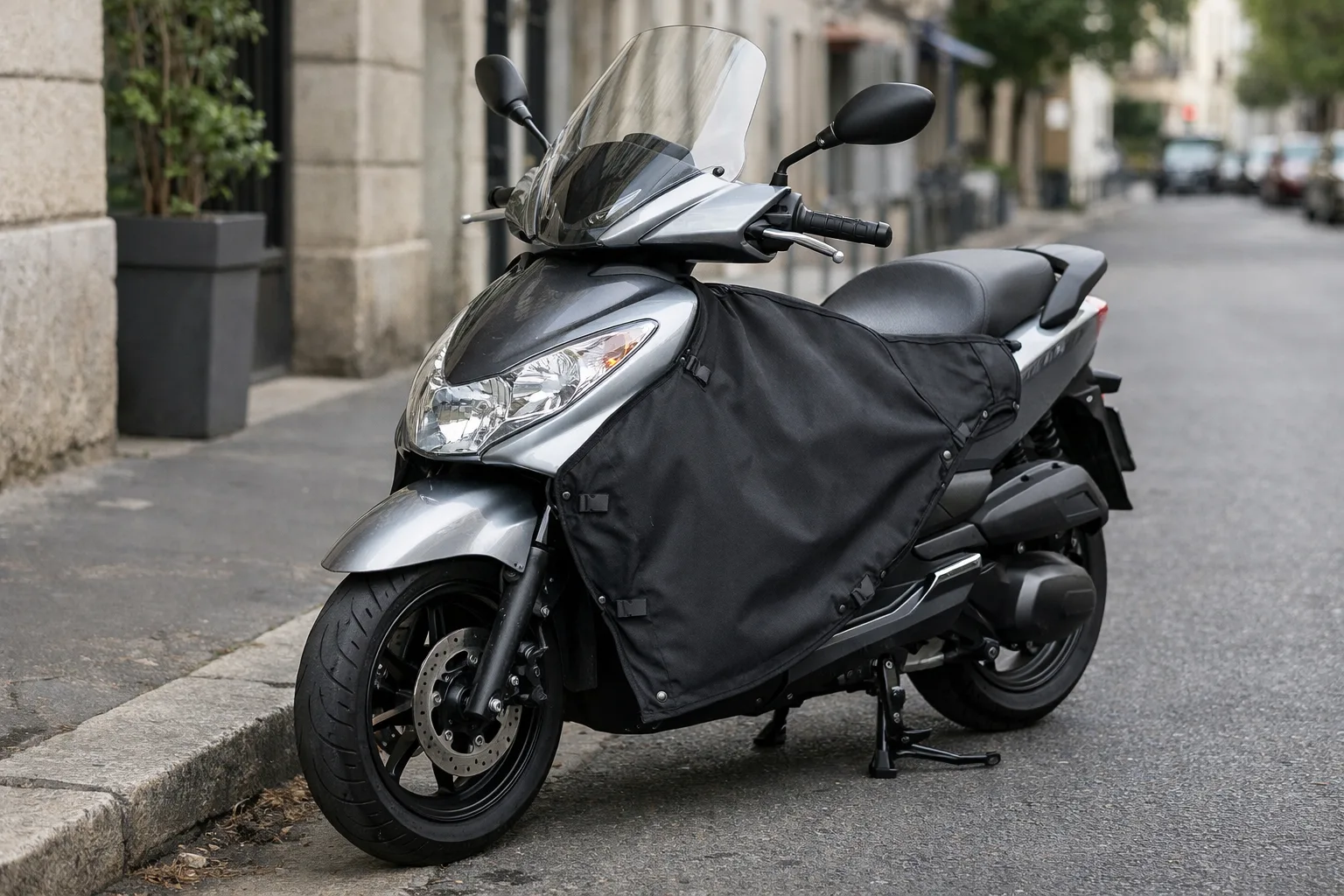 Scooter équipé d’un tablier textile fixé à l’avant et couvrant la zone des jambes.