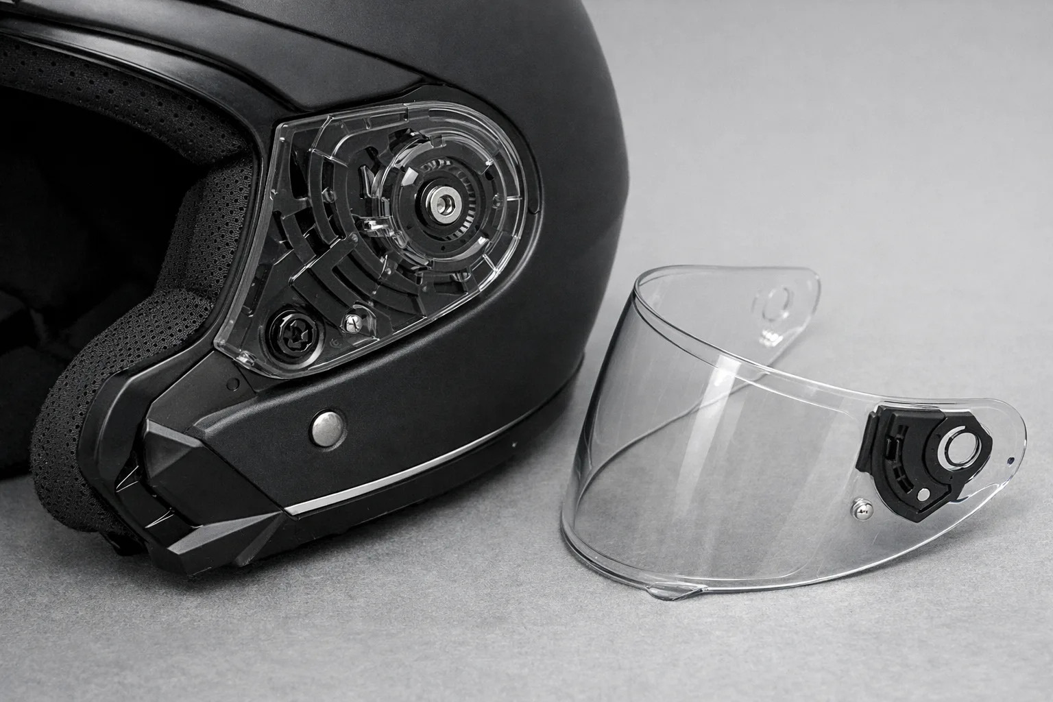 Attaches latérales d’un casque de moto et visière détachée posée à côté.